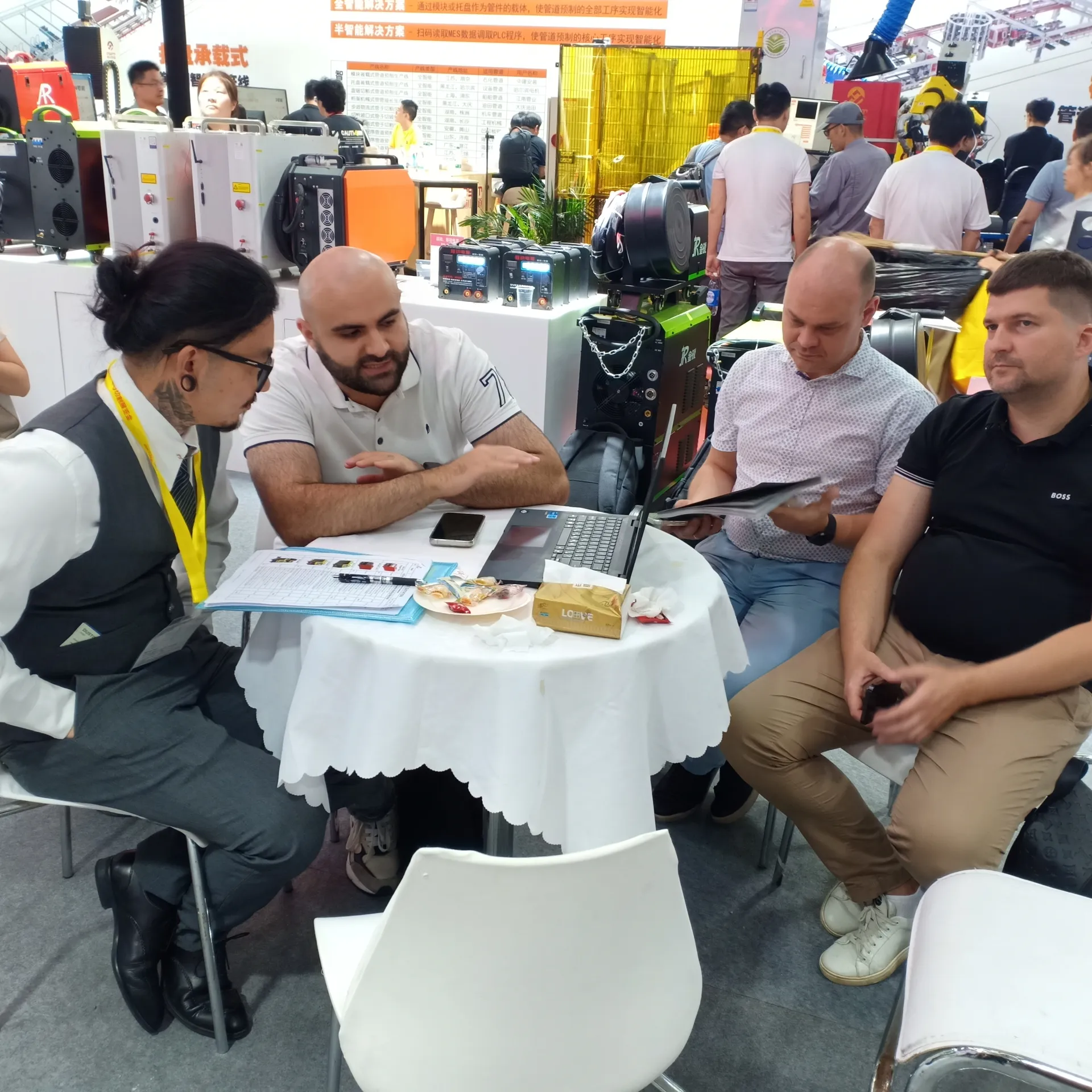 Distributor and buyer discussion at a welding equipment exhibition booth.