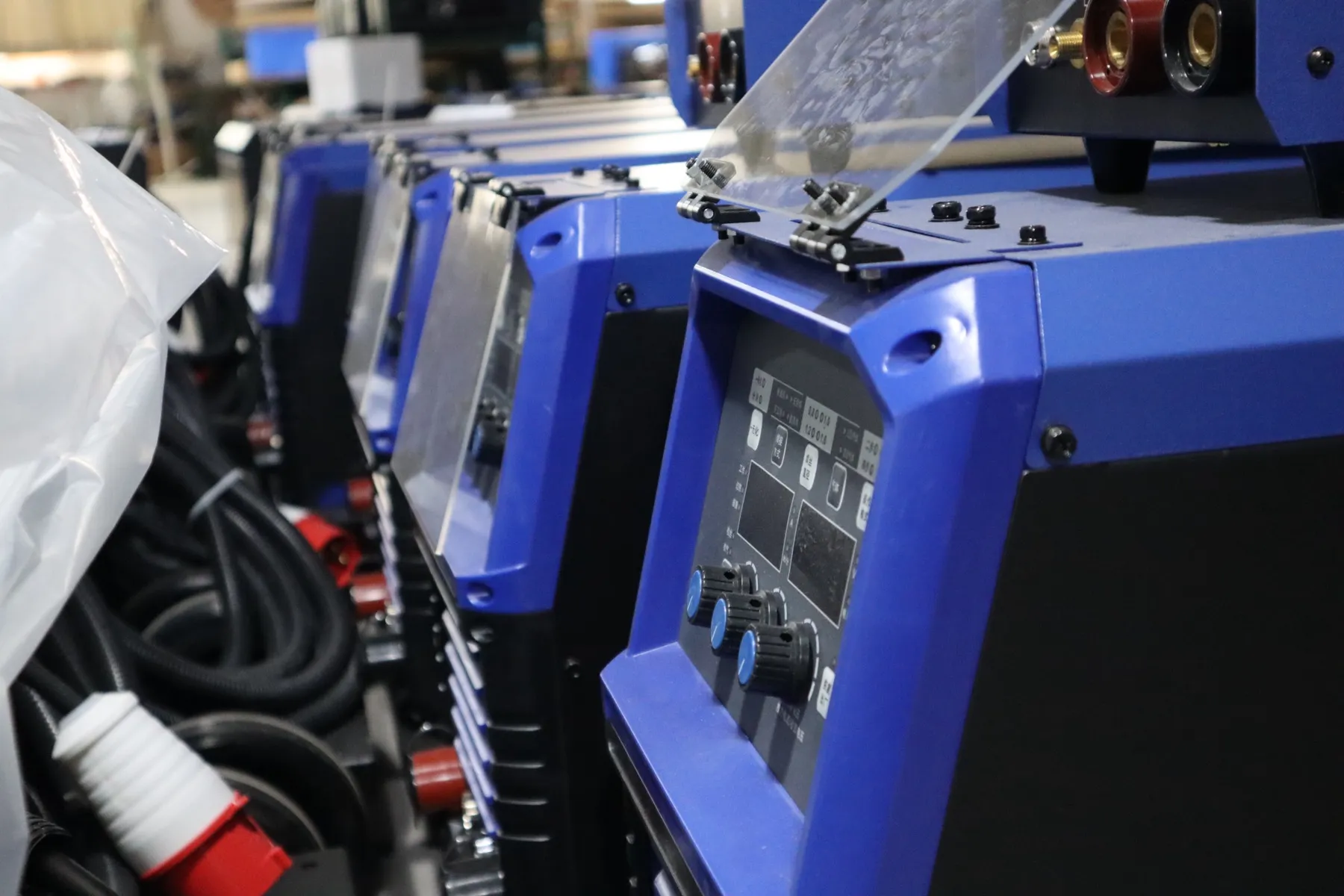 Blue welding machines in a factory line showing front-panel labels and model details.